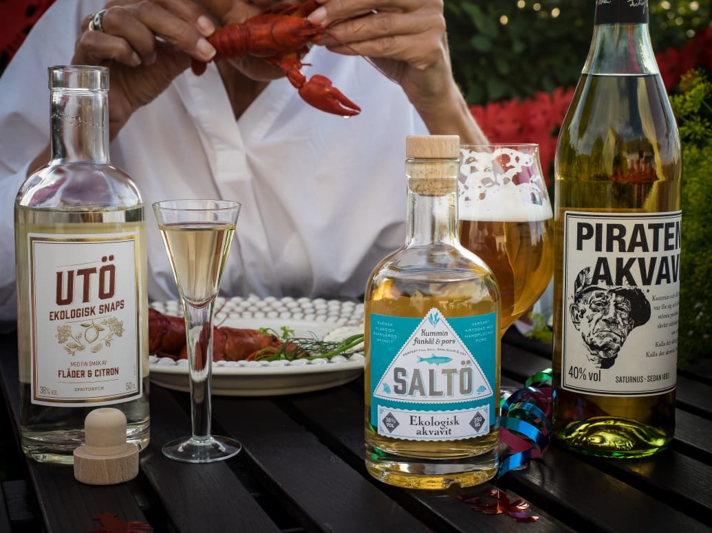 Swedish akvavit and snaps glasses set beside crayfish on a summer table